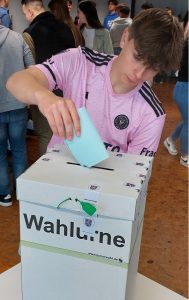 Eine Schüler wirft seinen Stimmzettel in die Wahlurne.