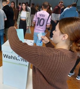 Eine Schülerin wirft ihren Stimmzettel in die Wahlurne.