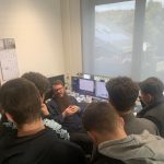 Das Bild zeit die Elektrotechnikerinnen und Elektrotechniker in einem Labor von Canton im Gepräch mit einem Mitarbeiter von Canton.