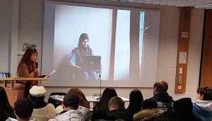 Auf dem Bild ist im Vordergrund Alea Horst zu sehen. Im Hintergrund kann man ein Mädchen mit einem Laptop erkennen.